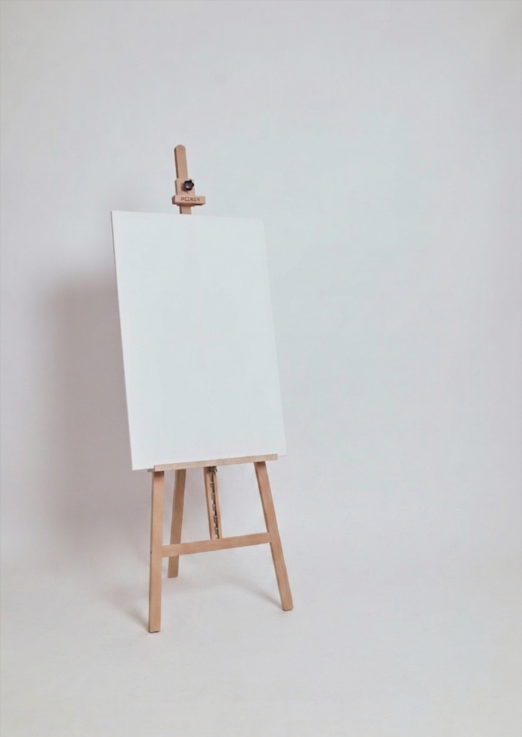 Empty white canvas on a wooden easel against a plain light-colored background.