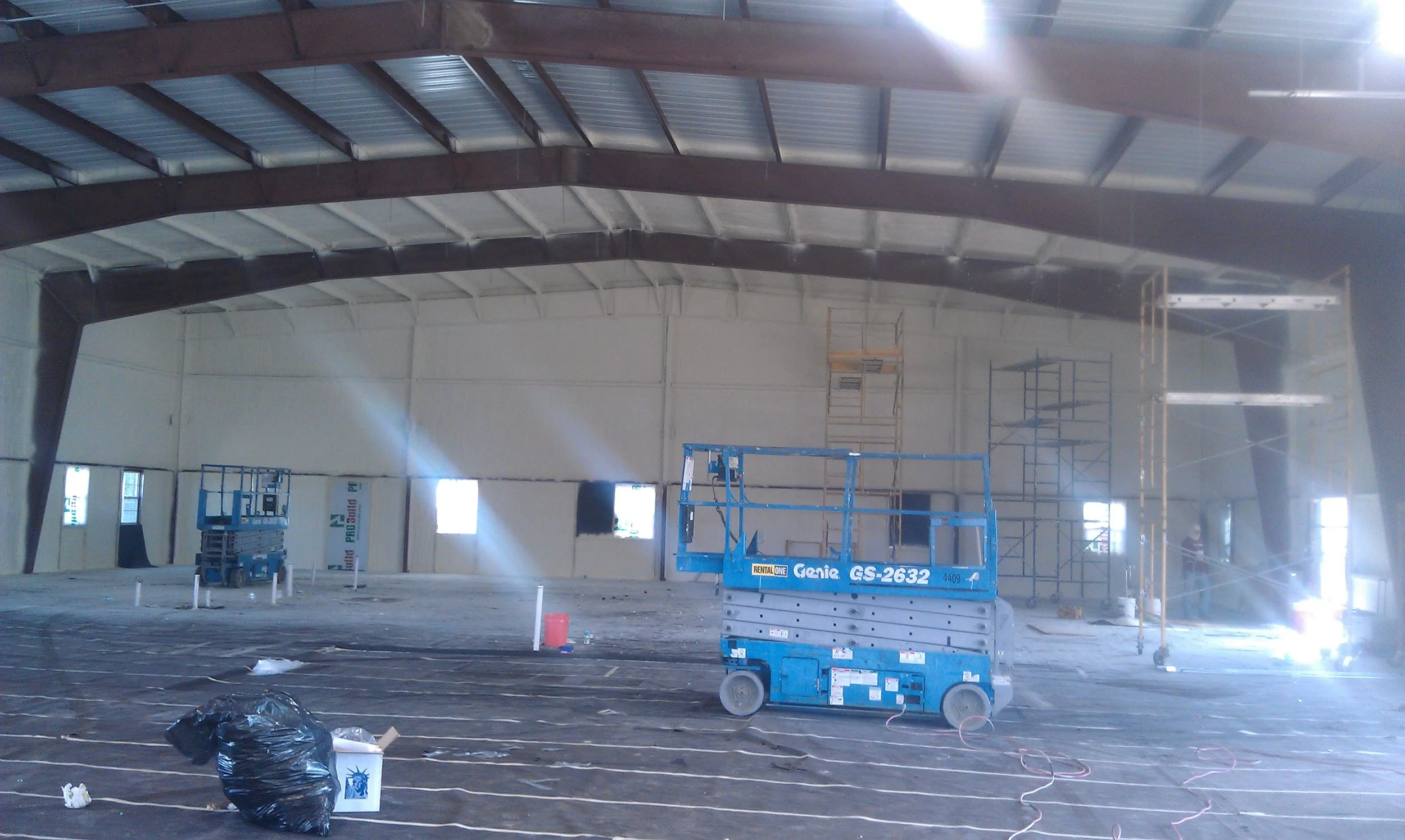 Construction site inside a large building with scaffolding, lift equipment, and ongoing interior work.
