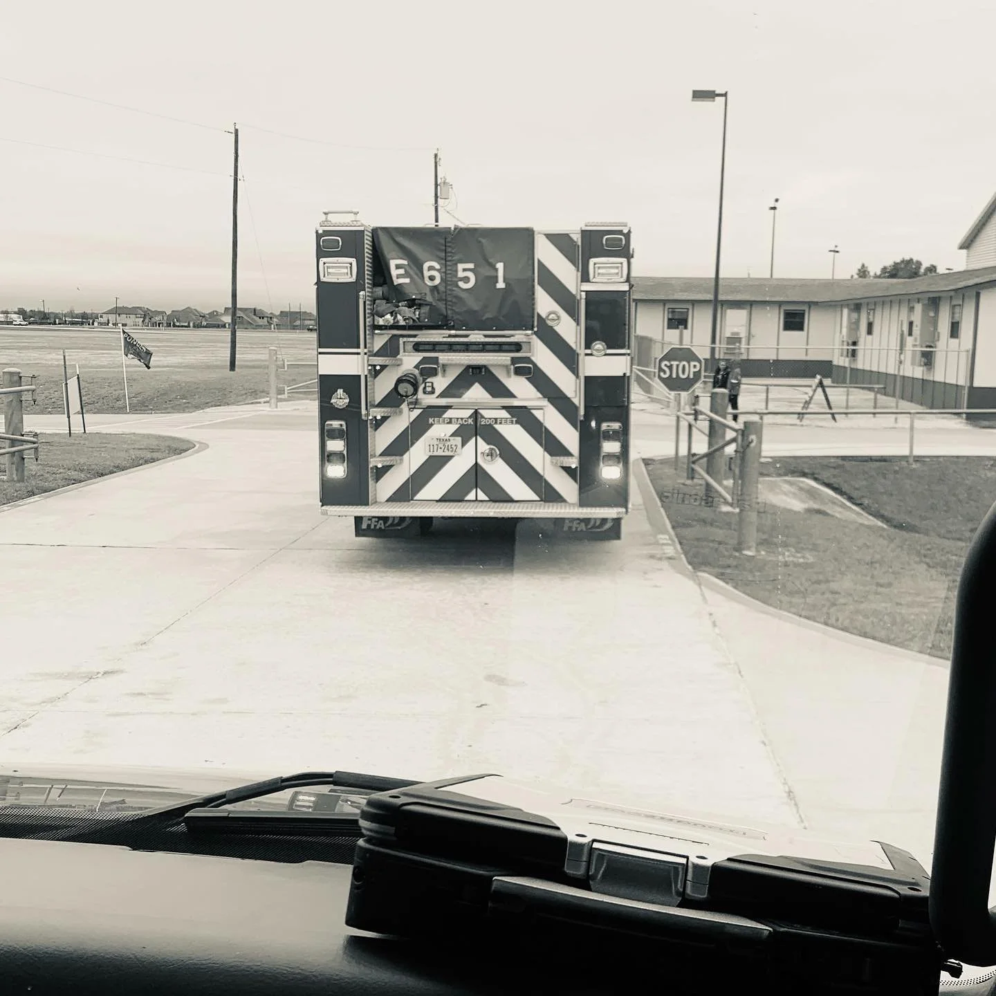 Fire truck with identifier E651 waiting at a stop sign at an intersection in a neighborhood.