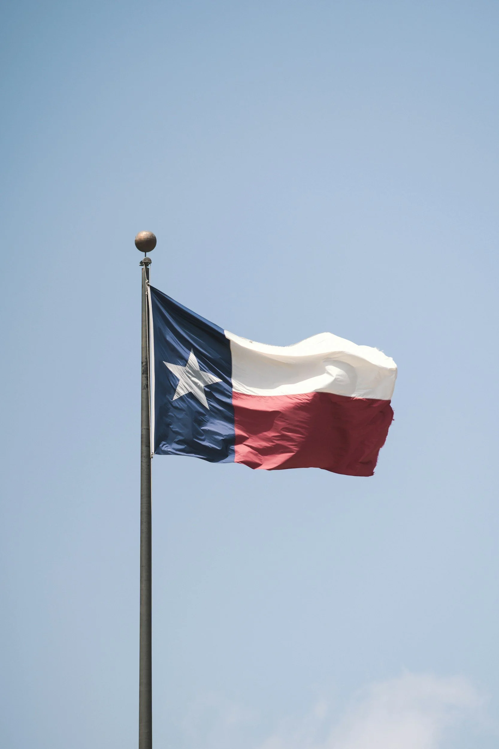 Texas state flag flying in the wind against a cloudy sky