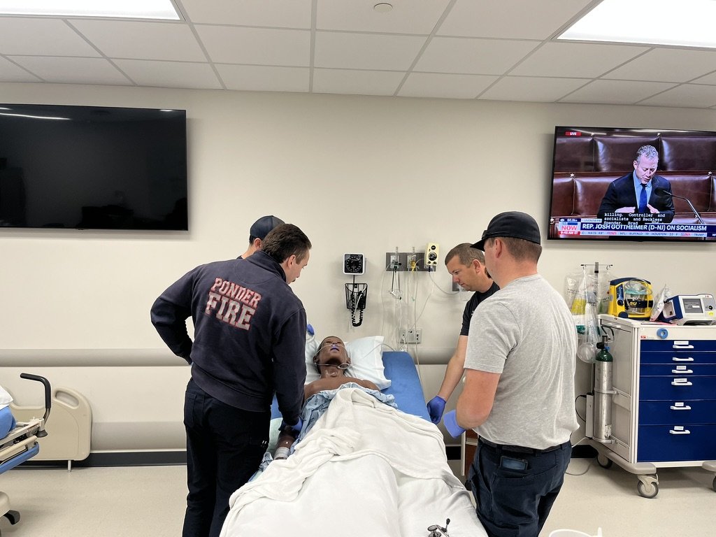 Emergency responders attending to a patient in a hospital room.