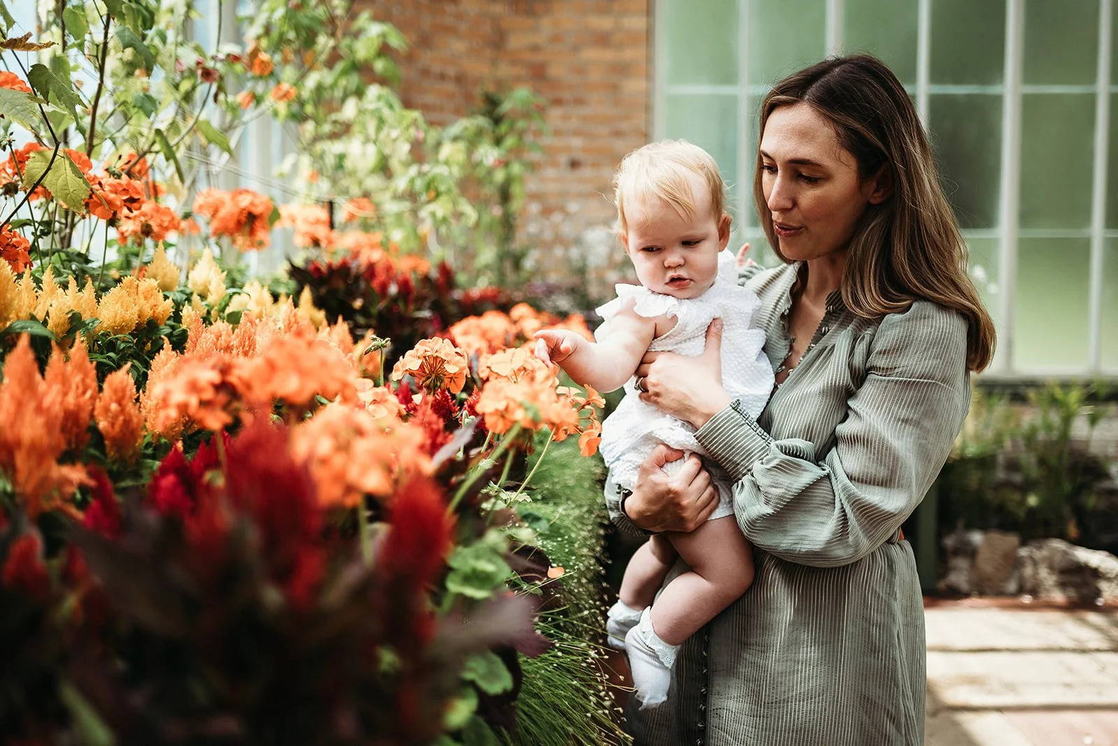 Haley Blackwood, founder of tend, holding a young child among garden flowers