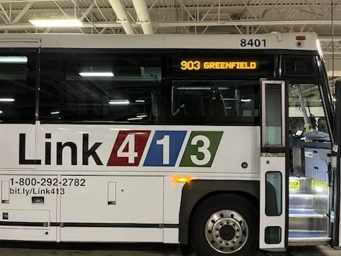 A Link413 Western Massachusetts commuter bus inside the PVTA garage with route number 903 to Greenfield displayed on the curb-side electronic sign