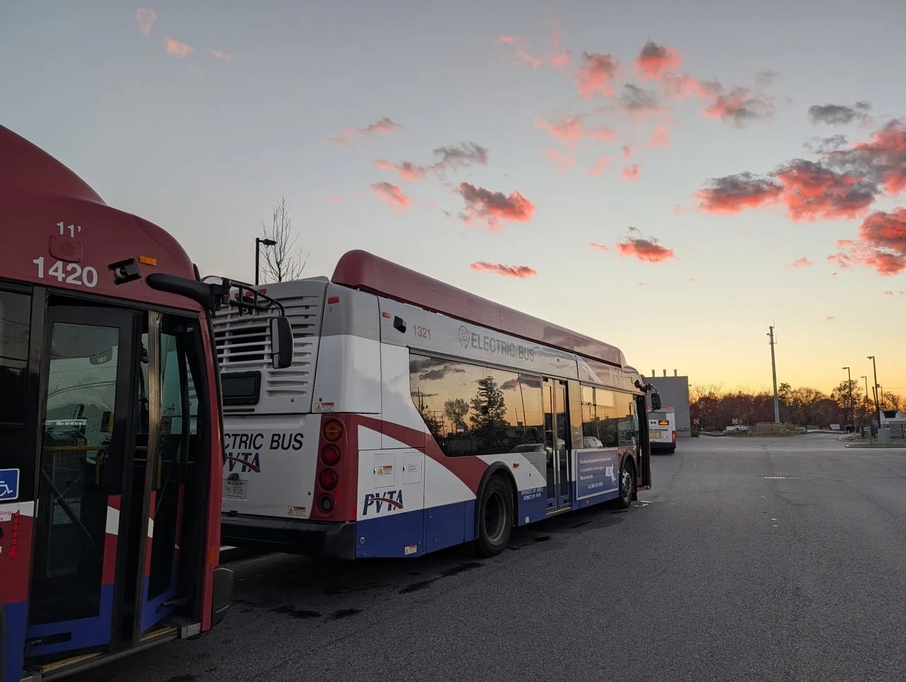 electric transit buses in the foreground  with a late summer sunset in the background.
