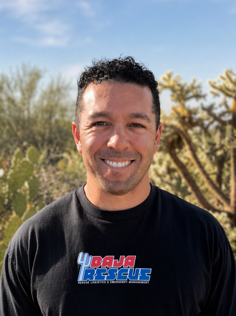 A smiling man taking a selfie on the beach with waves and a wooden pier in the background.