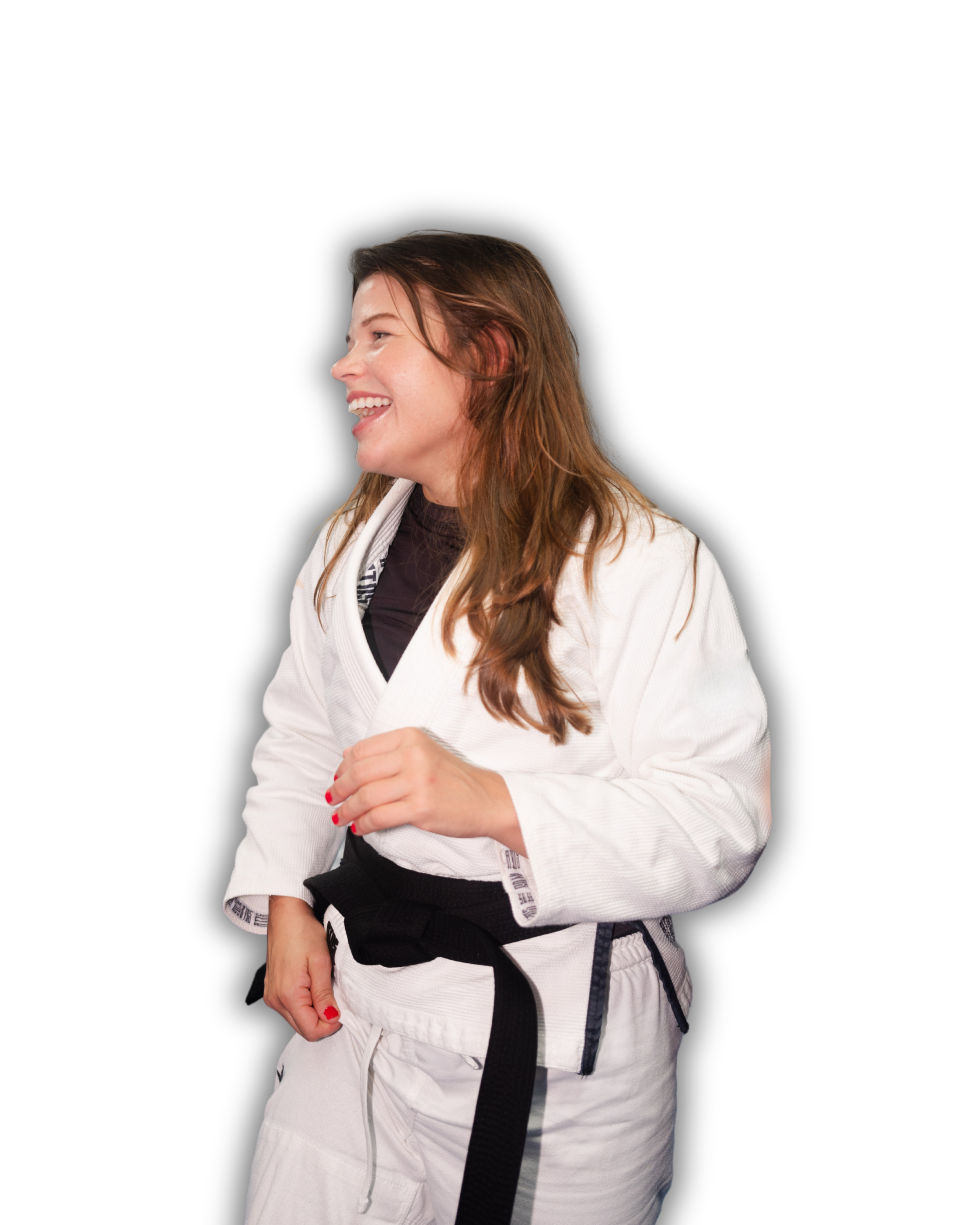 A young woman wearing a white martial arts gi with a black belt, smiling and looking to the side against a black background.