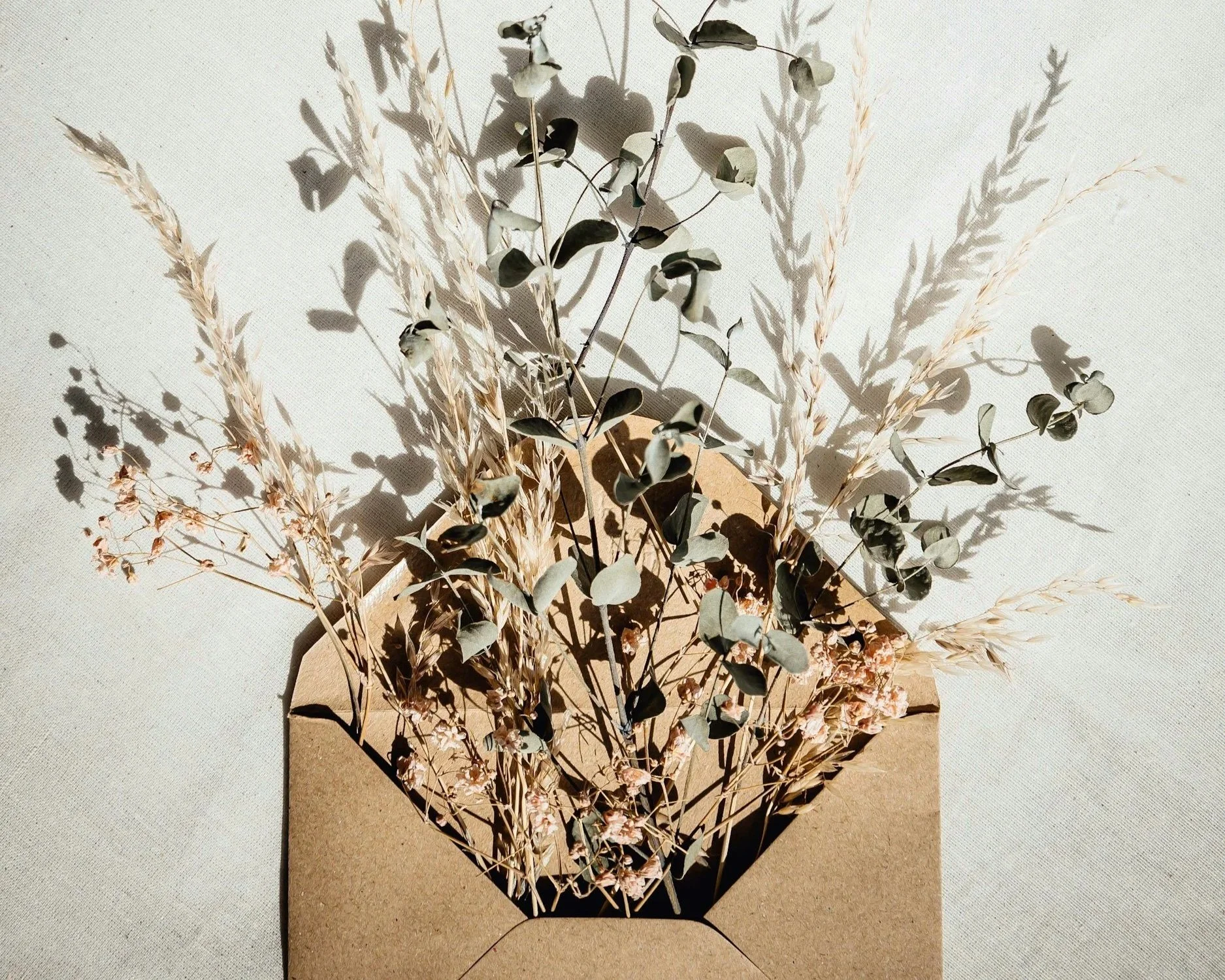 Custom Poem vs Greeting card - an image of an envelope with dried flowers coming out of it, symbolizing how words can blossom into beauty