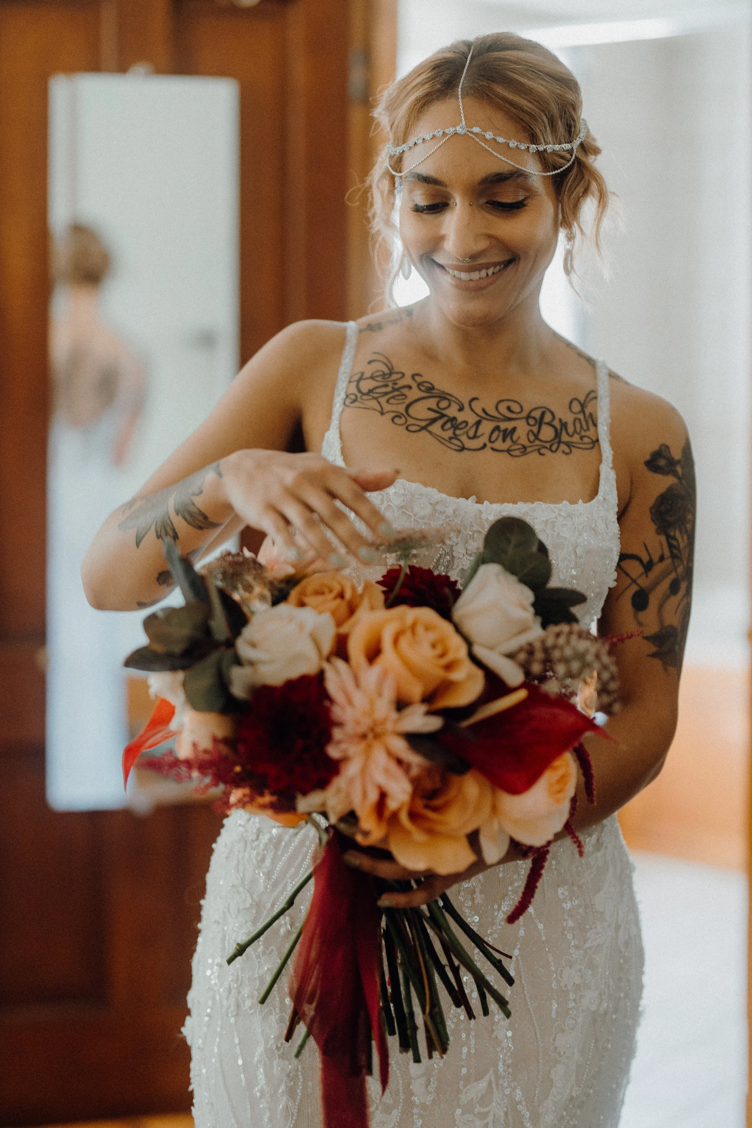 Bride in white lace dress holding bouquet in doorway