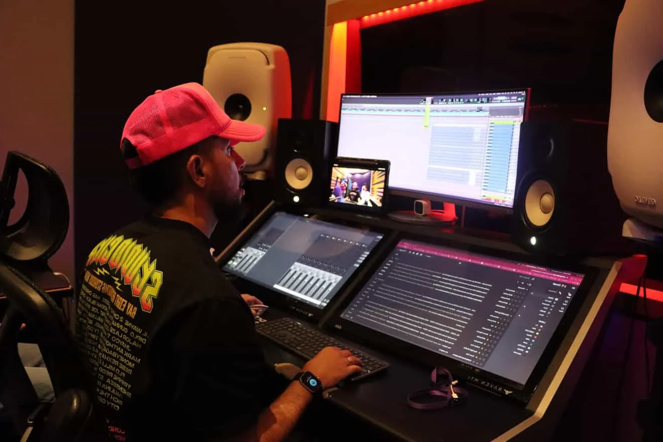 Persona en un estudio de grabación ajustando equipos de audio y producción musical.