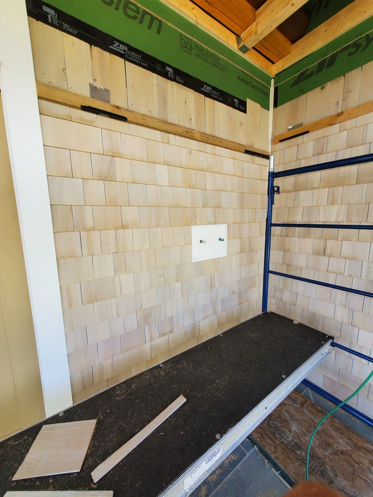 Construction site with wooden walls, some tile work, and exposed plumbing and wiring in a room under renovation.