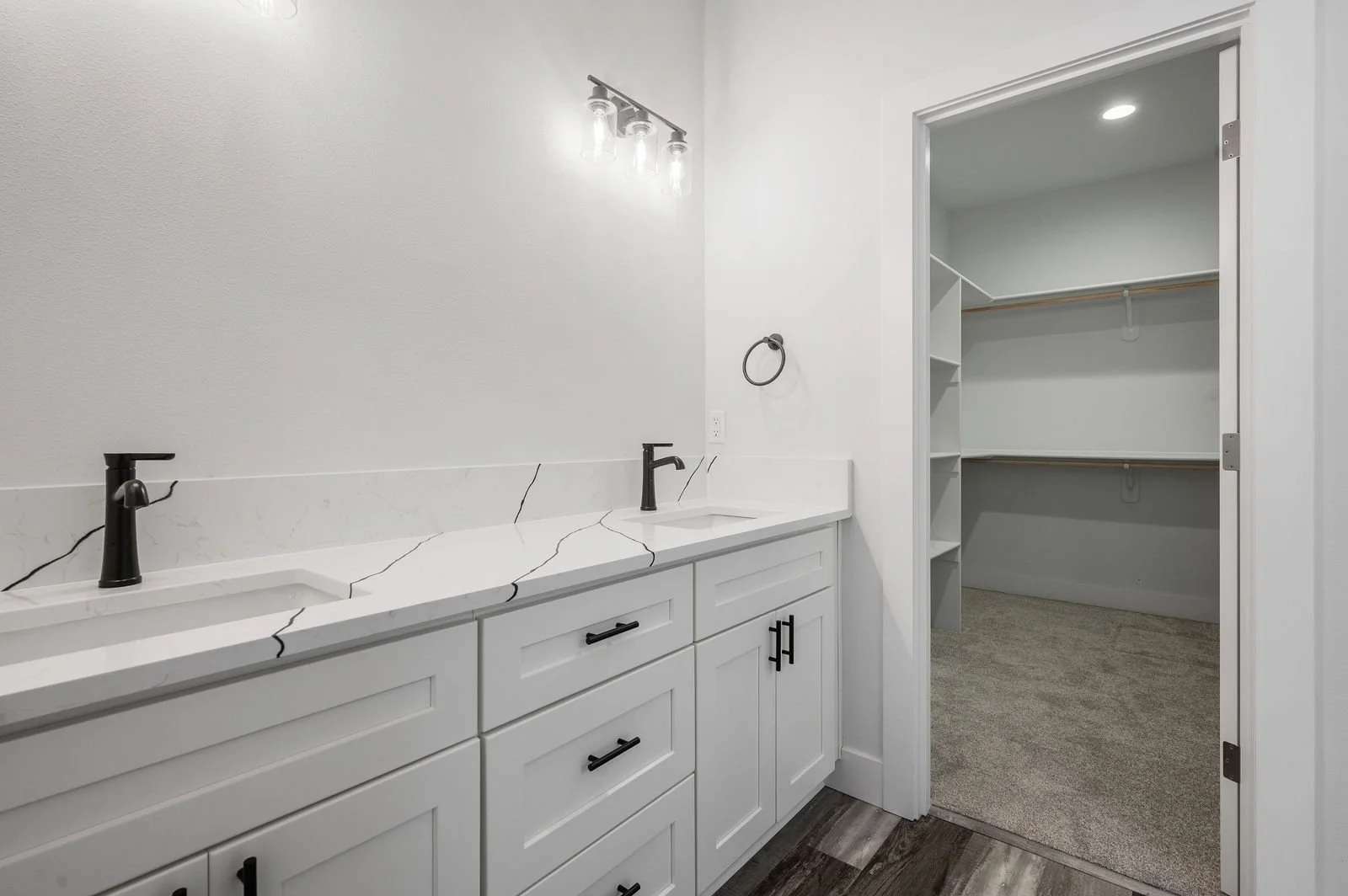 Professional real estate photography and drone imagery- Of bathroom with dual sinks and walk-in closet. 