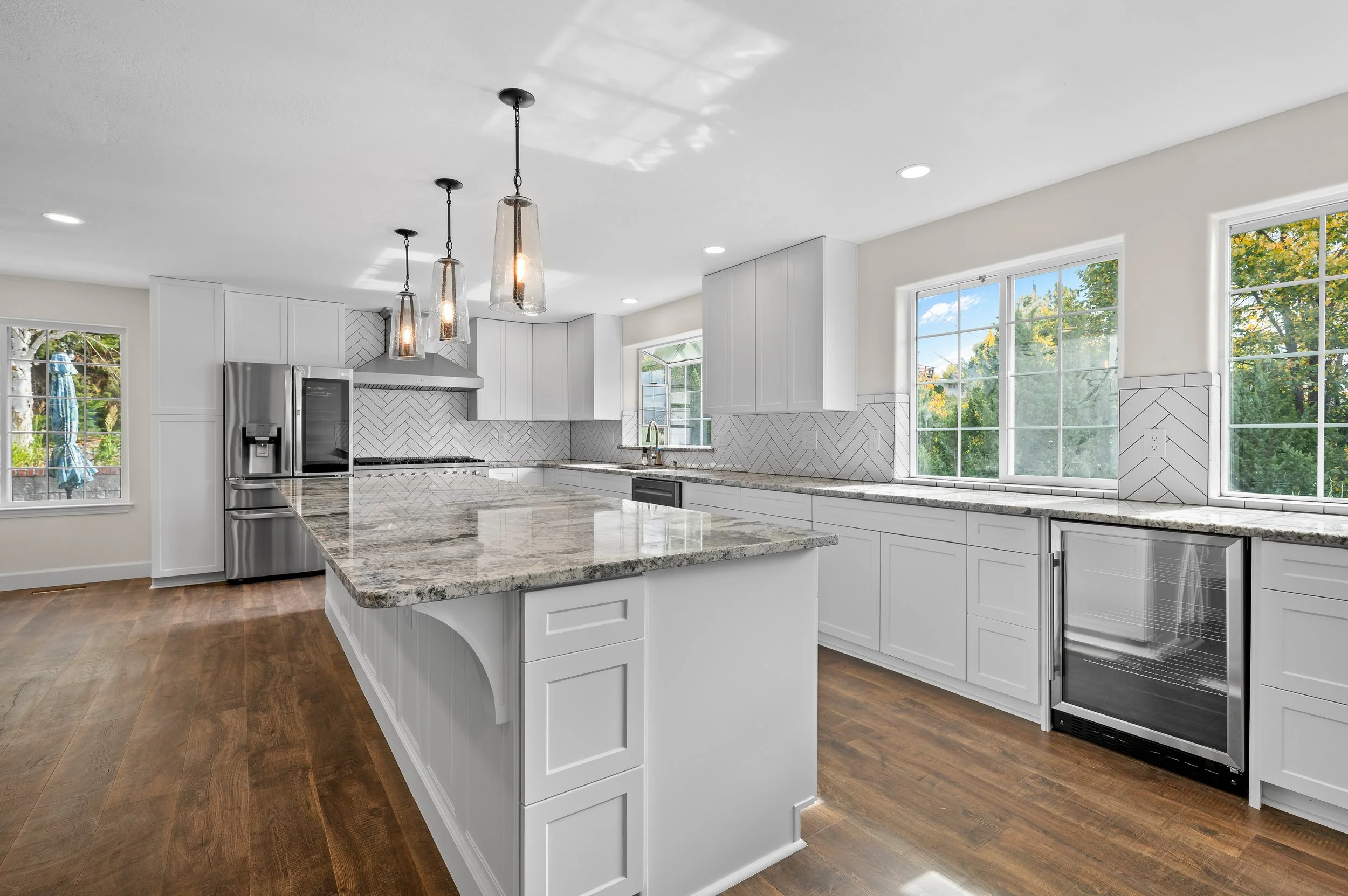 White kitchen with high-end finishes and granite counters. Newly installed appliances in an overview photograph.