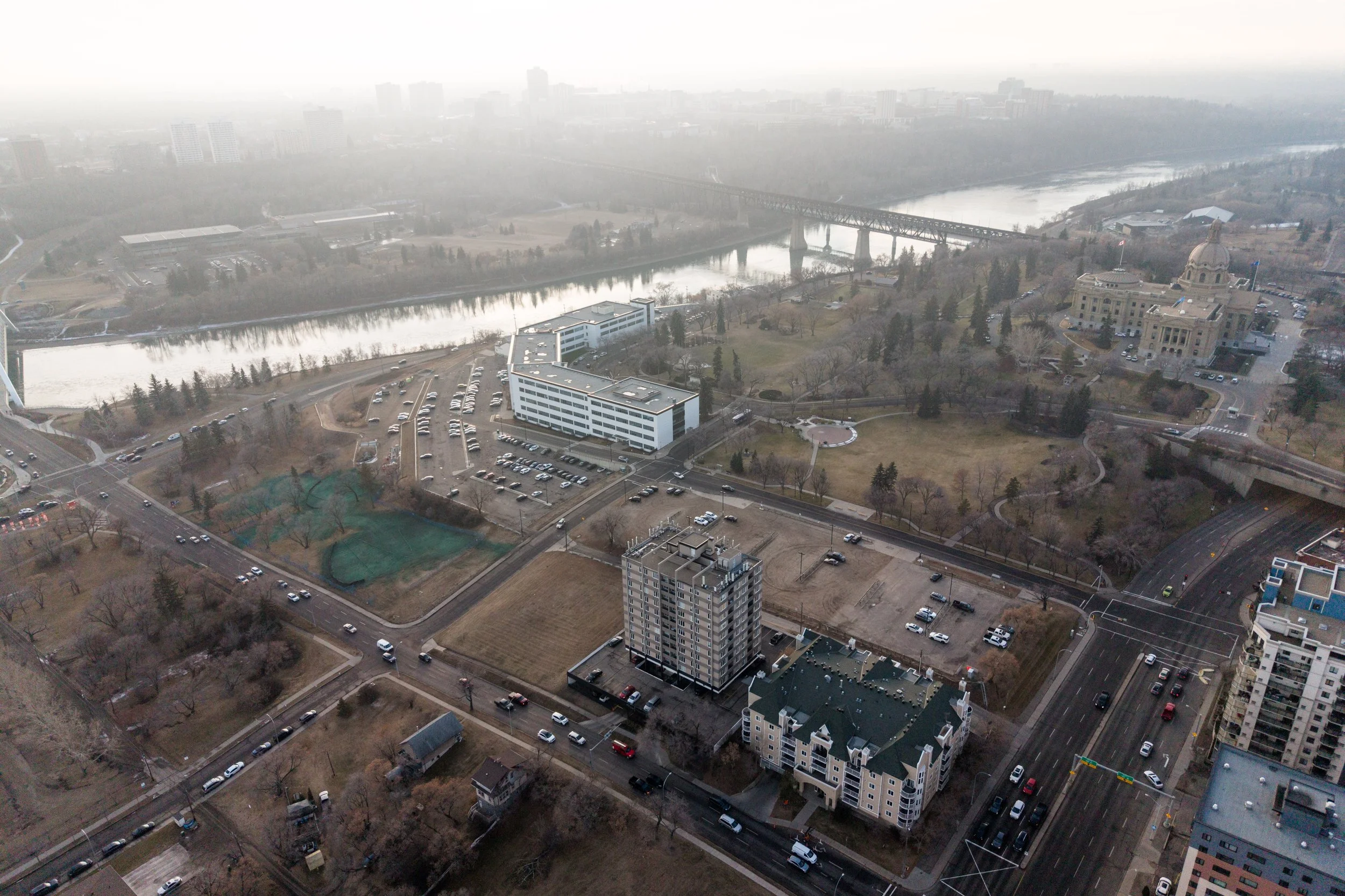 Aerial view of a cityscape with a river, bridge, buildings, and roads in the daytime.