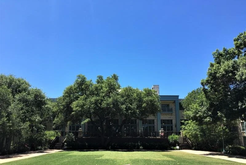 A mansion in San Antonio covered by green trees.