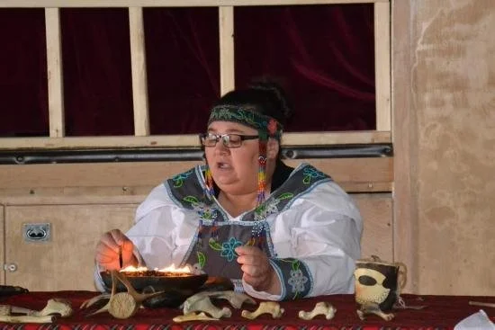A woman dressed in colorful, ingidenous clothing lights the Quliq