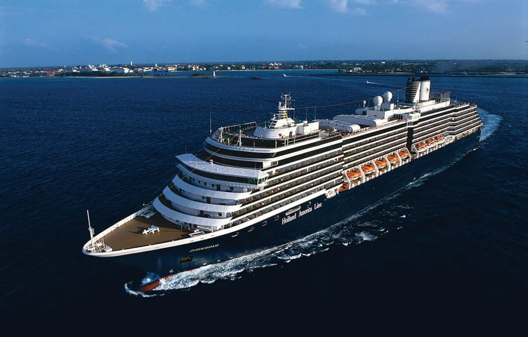 A large cruises ship at sea with New England in the background.