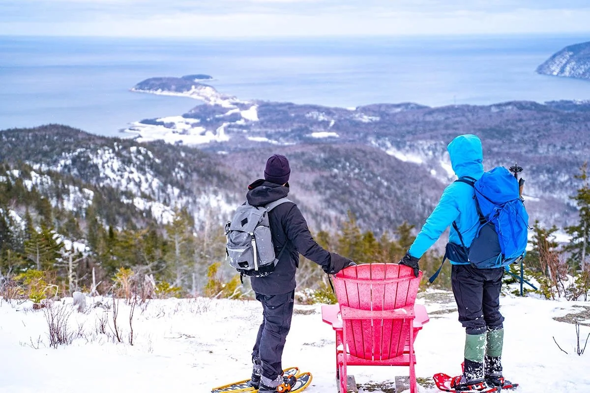 Two snowshoers overlook the mountains and sea in Nova Scotia.