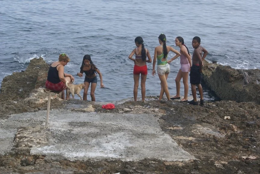 A group of kids in swimsuits play by the water in Havana, Cuba.