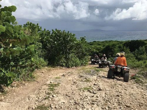 Tourists take an ATV down a mountains towards the beach in Guadeloupe.