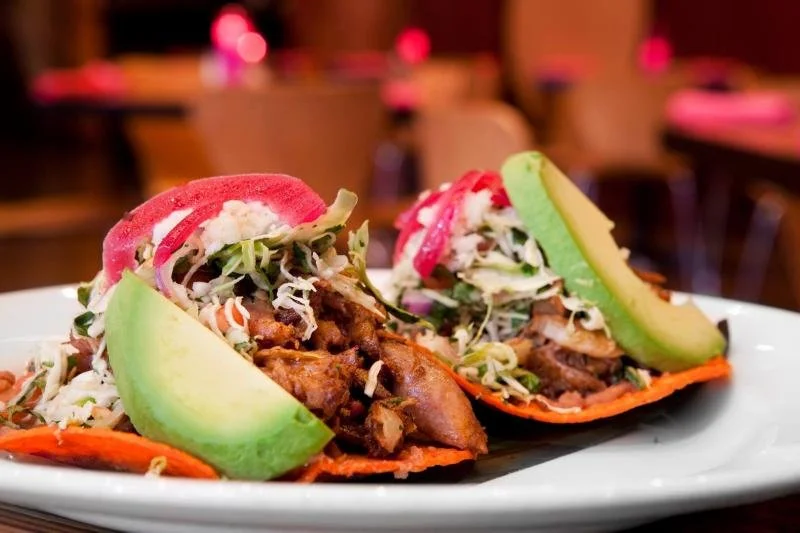 Big, green avocados sit upon tacos at Acenar in San Antonio.
