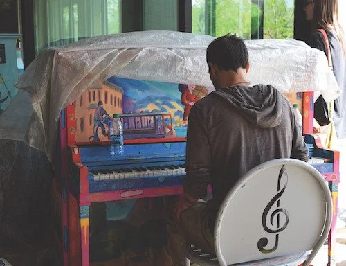 A man plays on a painted piano in Fort Collins.