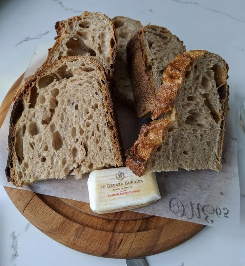 Homemade sourdough and French better on a wooden plate at ONE65.