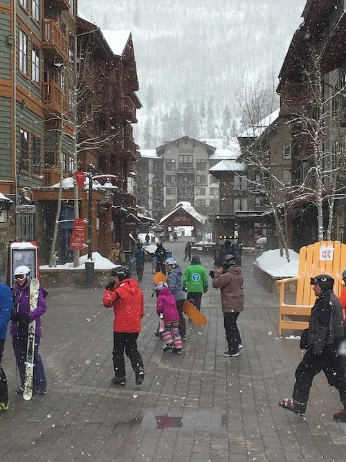 A group of skiers and snowboarders make their way to the slopes through Copper Mountain Village.