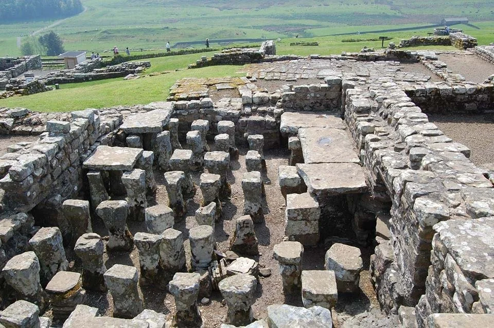 The ruins of Hadrians Wall with green fields in the background.