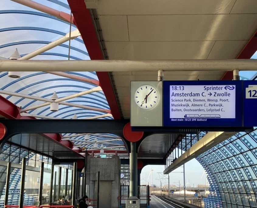 A train station in Amsterdam surrounded by clear windows.