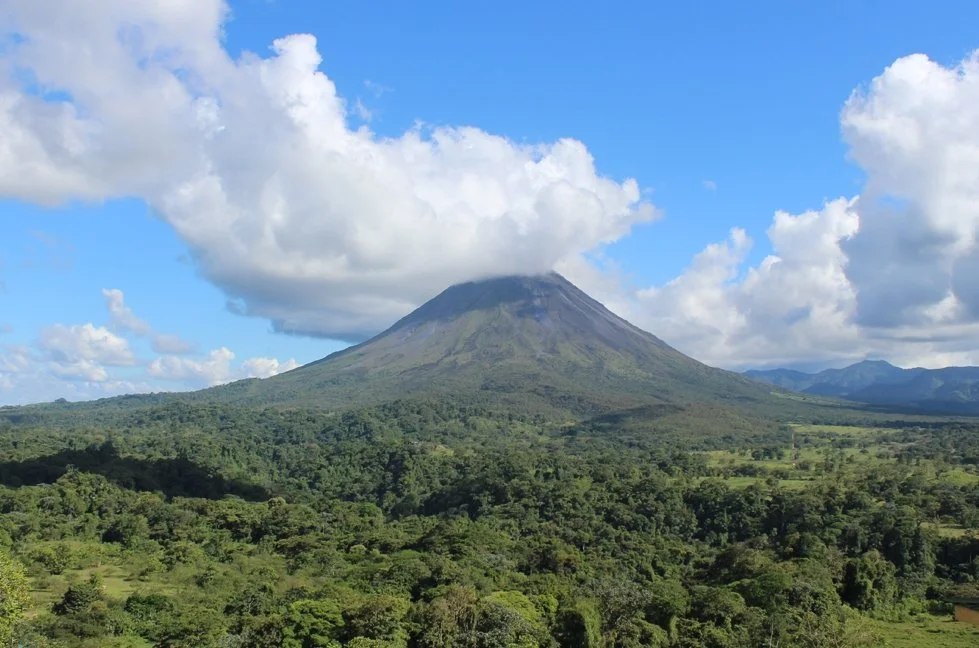 A volcano towers over surrounding forests and mountains in Costa Rica.
