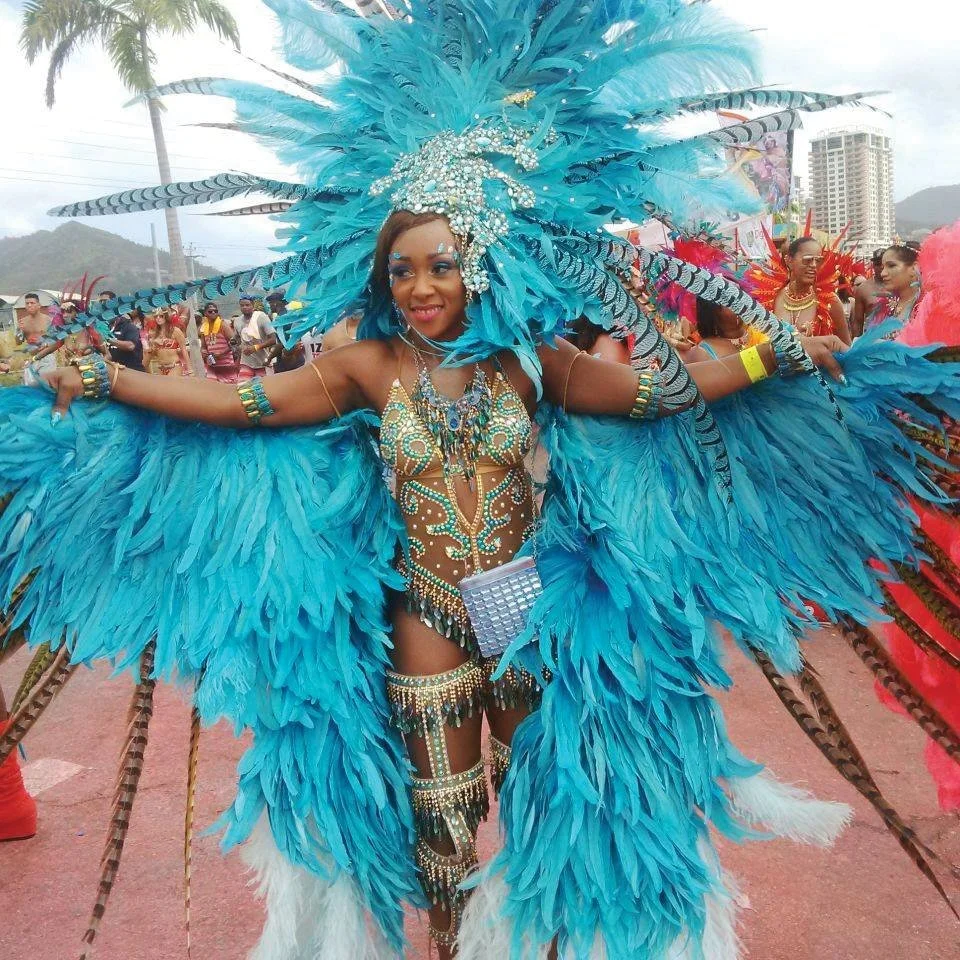 A woman covered in blue gems and blue feathers during Carnival.