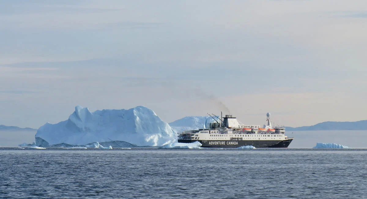 An adventure Canada cruise ship sails past icebergs in Ilulissat.