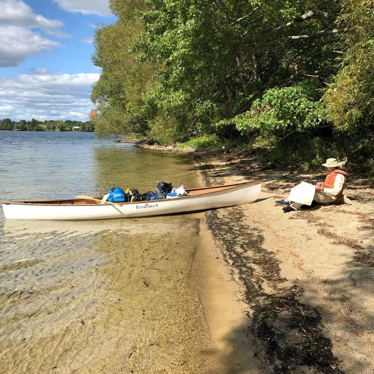 A man enjoys his lunch on the sand by Murphy Point Provincial Park.