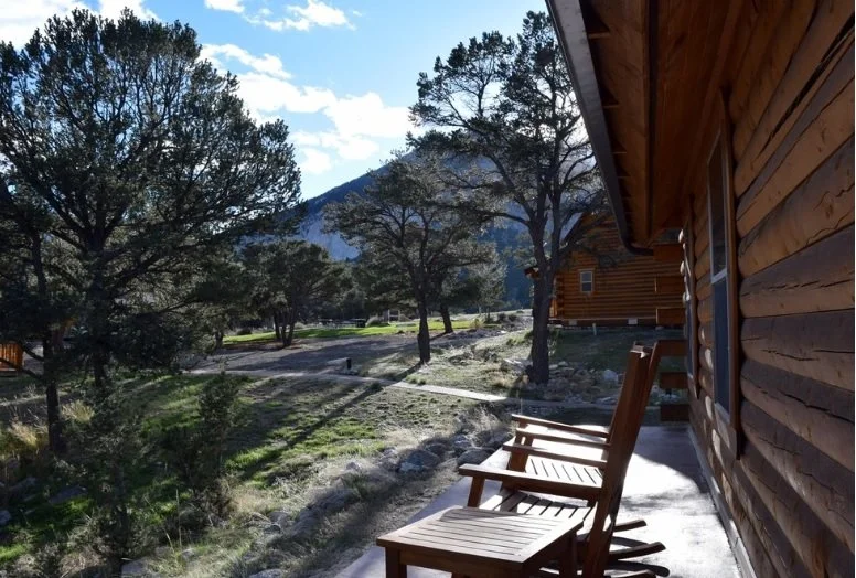 Two wooden chairs outside a log cabin overlooking Mount Princeton Hot Springs.