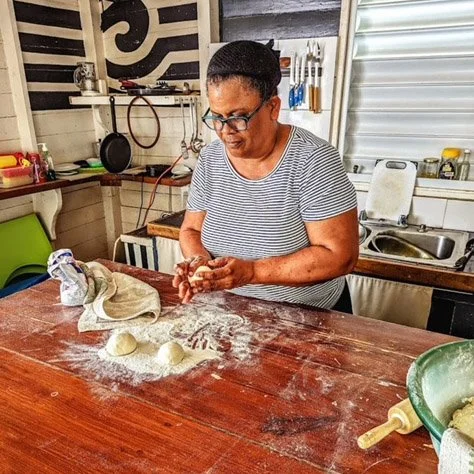 Roti Sue rolls three balls dough on a wooden table.