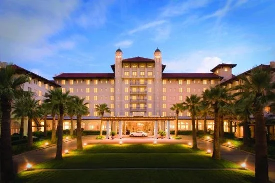 Palm trees line the entrance to a large mansion in Galveston.