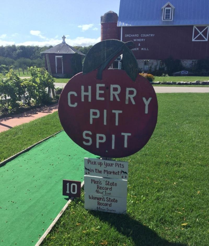 A large red cherry sign labeled "cherry pit spit".
