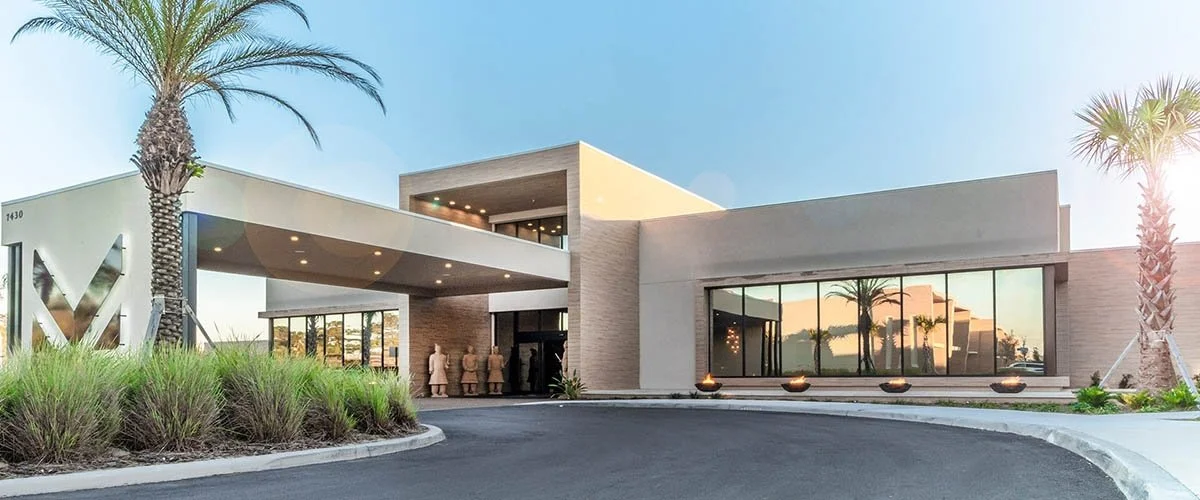 Light concrete and reflective windows at The Clubhouse at Magic Village Views.