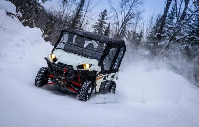 Tourists make their way through snow mounds on dune buggy.
