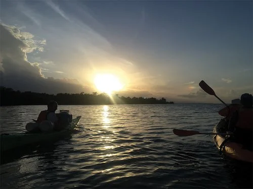 Kayakers are silhoutted during sundown by the Carribean Sea.