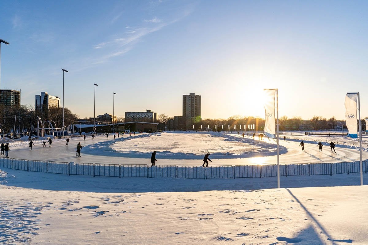 Groups of skaters ice skate around a circle during sunset.