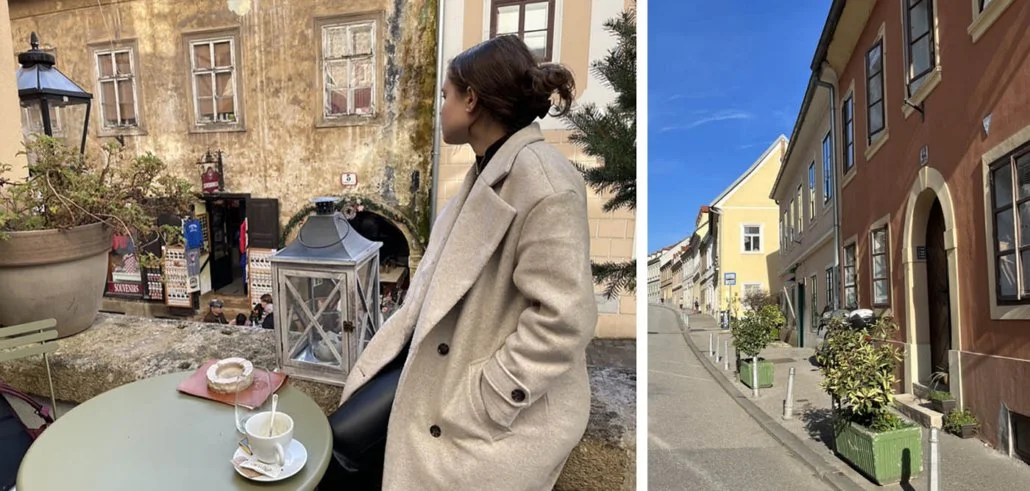 A girl sits at a cafe in Zagreb overlooking a wooden building.