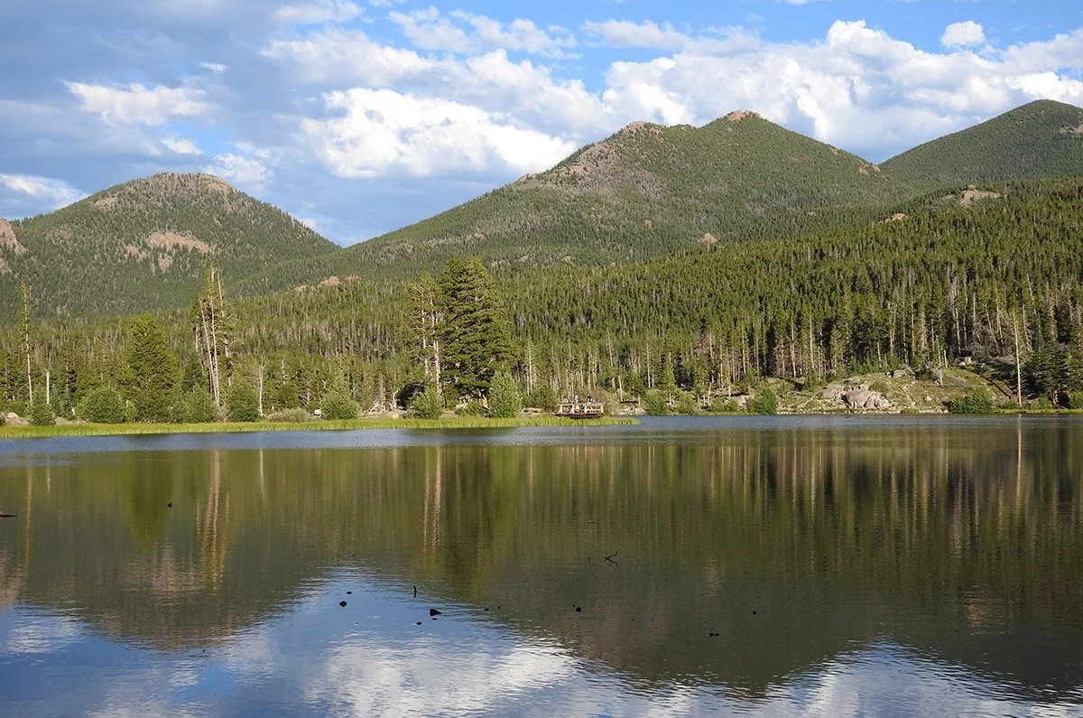 Mountains and trees reflect in Sprague Lake, Estes Park, Colorado.