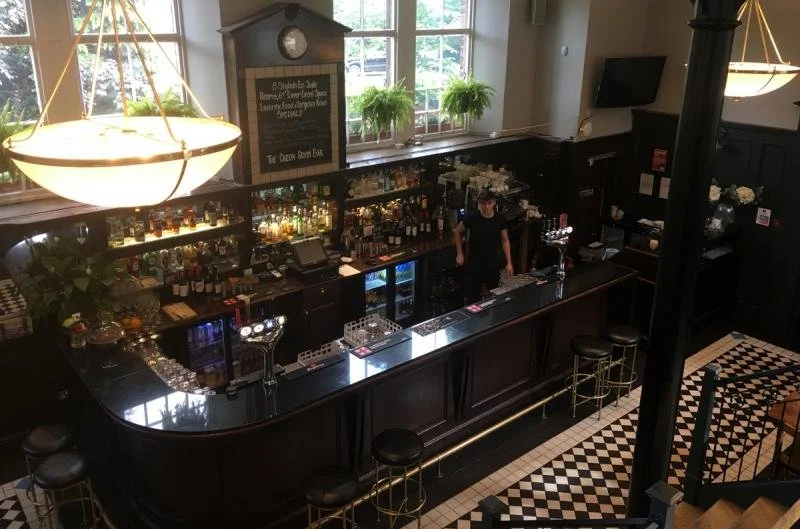 Bright lights and cabinets of liquor at the Green Room Cafe bar in a baronial-stye Cathedral House Hotel.