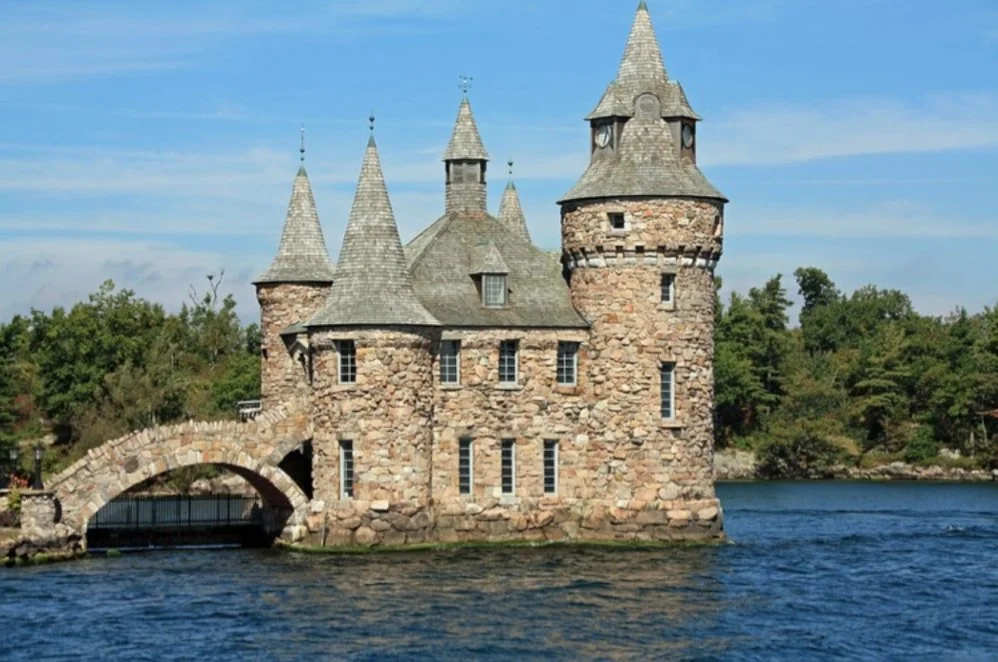 A large brick building towers over a river with trees in the background near Ottawa.