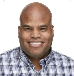 Close-up of a smiling man with a bald head, wearing a plaid shirt against a white background.