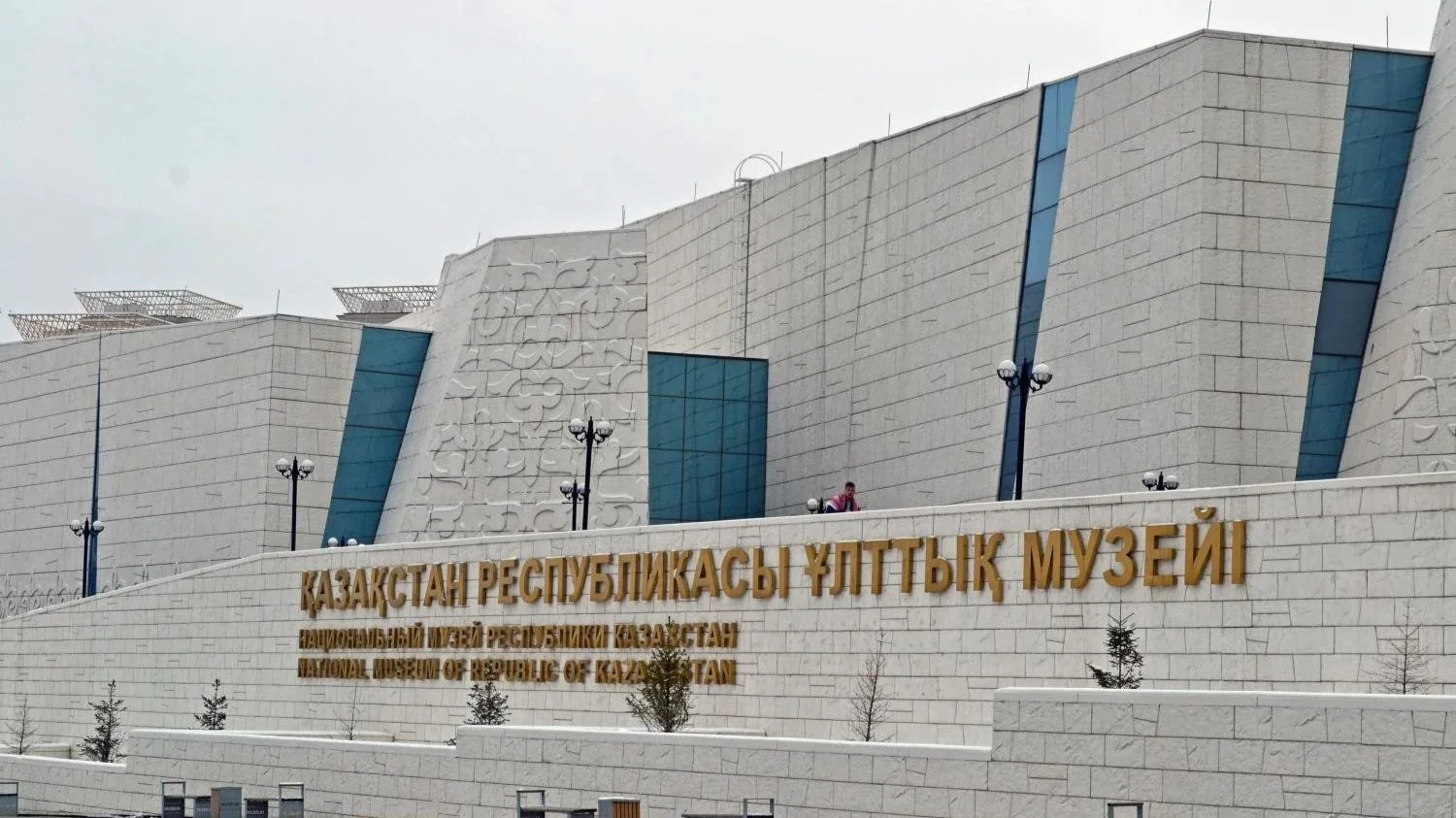 A large brick and glass building besides the sign of the National Museum of the Republican of Kazakhstan.
