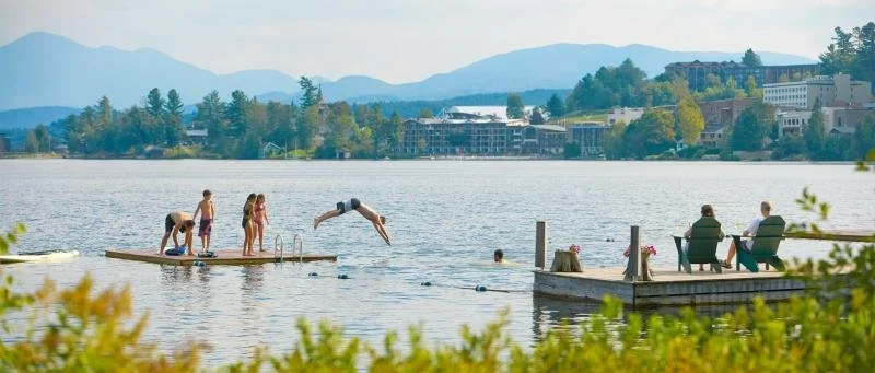 A group of visitors dive into Mirror Lake in the summer outside of Mirror Lake Resort and Spa.