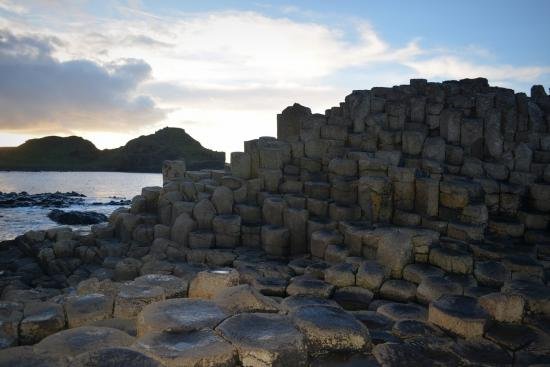 A stack of rocks at Giants causeway as bright lights from the sunset reflect in the sky.