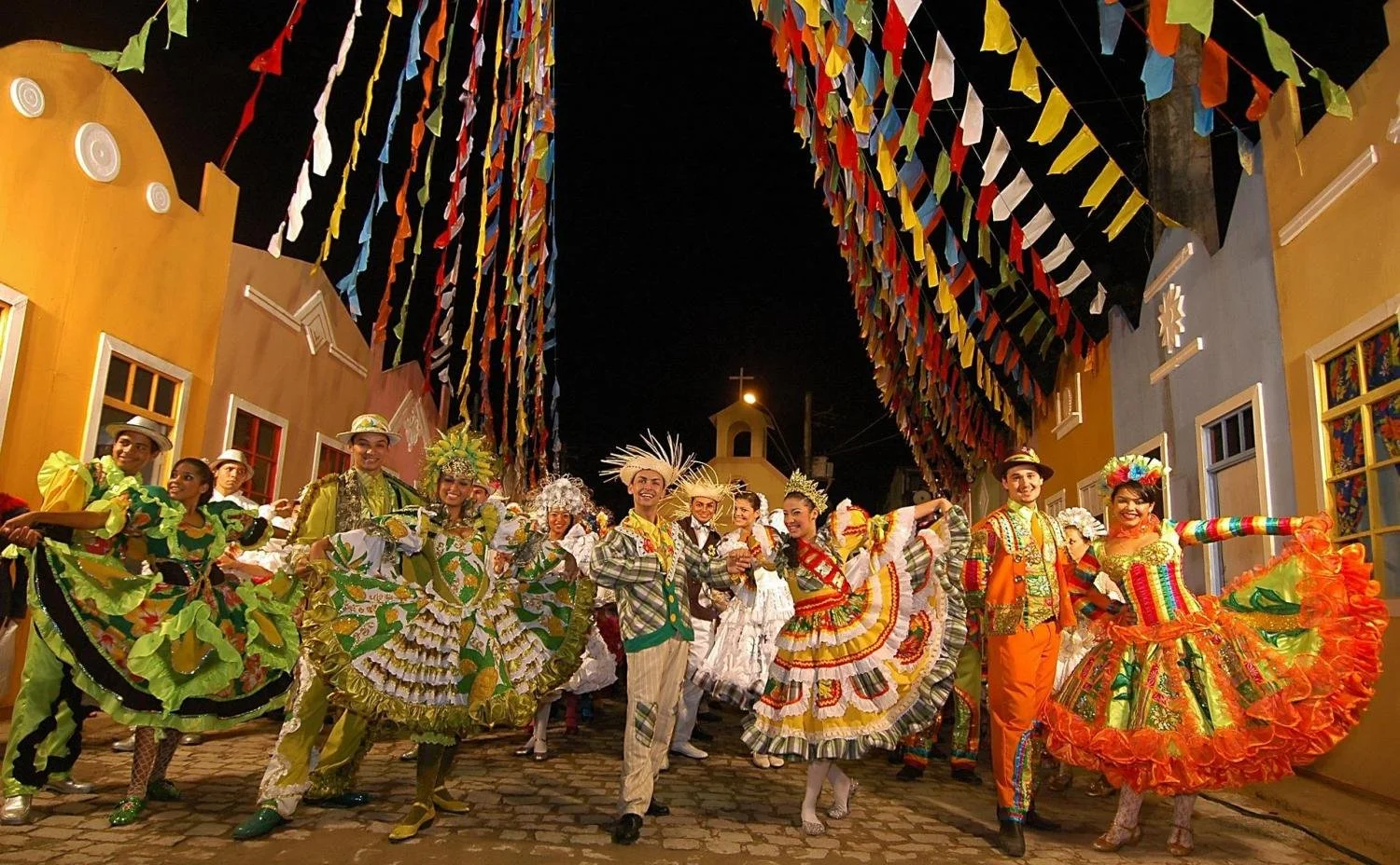 A group of men and women in brightly coloured clothes dance in the street of Brazil.